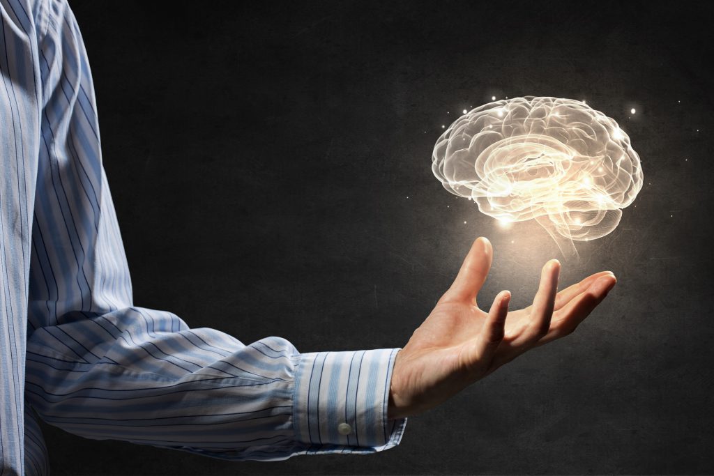 Close up of human hand holding brain illustration