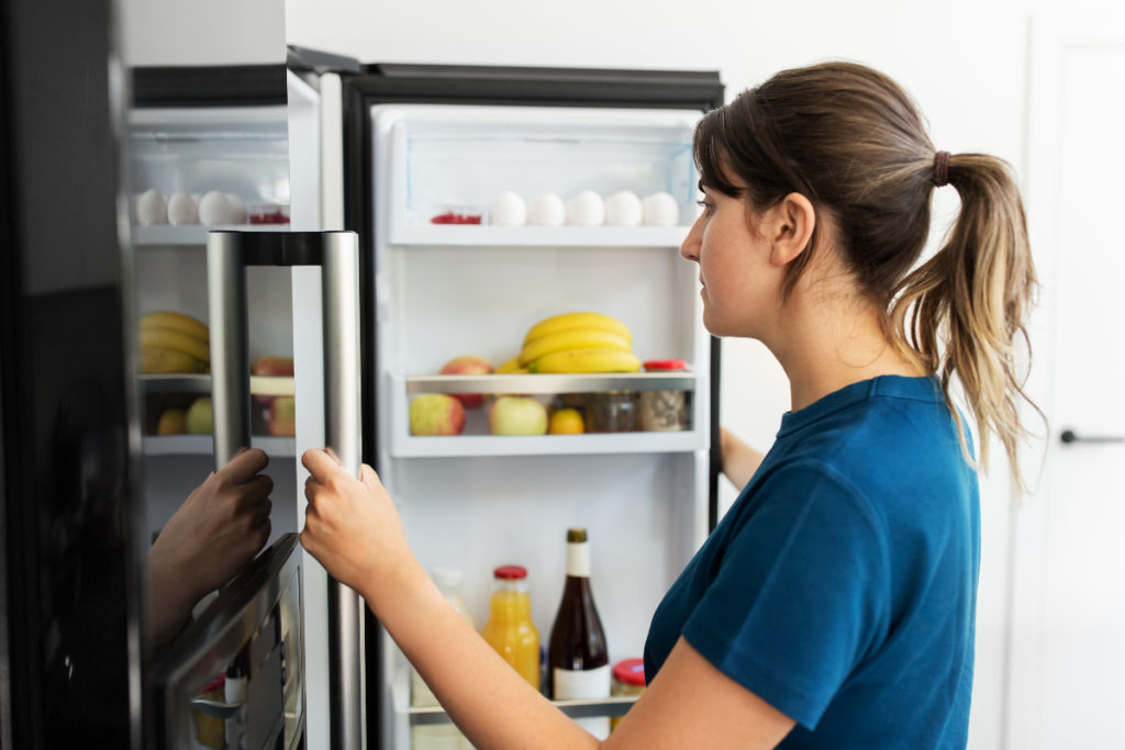 Woman standing in front of open fridge to illustrate 20 Most Weight-Loss-Friendly Foods On The Planet