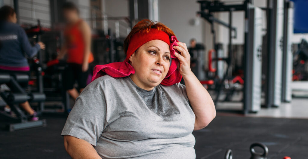 Tired woman sitting down at the gym to illustrate Consequences Of Not Taking Vitamins After Gastric Bypass