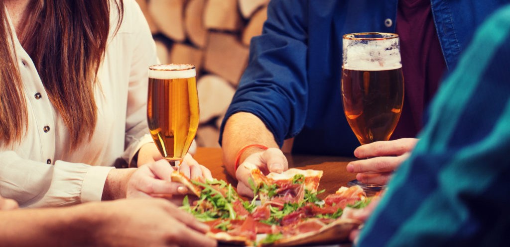 People enjoying pizza and beer to illustrate if you can have alcohol after weight loss surgery.