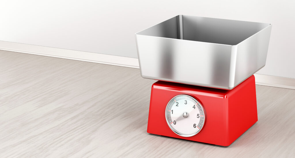 A red food scale with an empty metal bowl on top to illustrate How Many Calories Should I Eat After Gastric Sleeve?